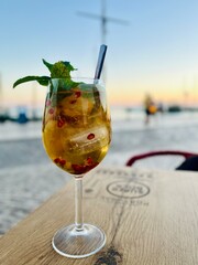 Verre de sangria blanche avec fruits frais – cocktail estival devant un port pittoresque