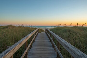 Obraz premium Timber trail stretching toward a sandy shore with dunes under a sunset sky