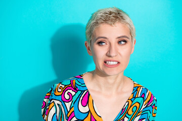 Portrait of a stylish woman with short blonde hair against a turquoise background showcasing vibrant clothing