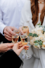 Elegant wedding toast with champagne and white rose bouquet in brides hand