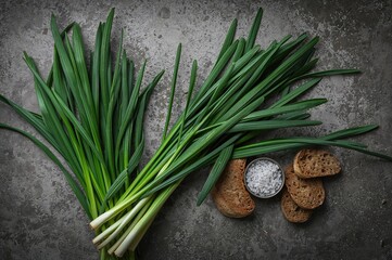 Freshly gathered wild garlic leaves arranged with bread and salt on a neutral surface