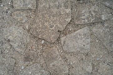 Detailed view of a stone walkway featuring uneven flagstones embedded in a layer of tiny stones, showcasing natural textures and warm, earthy colors for a rustic atmosphere.