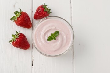 Mint-infused strawberry yogurt served on a rustic white wooden surface