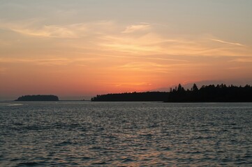 Naklejka premium Silhouetted Trees Against a Sunset Over the Ocean