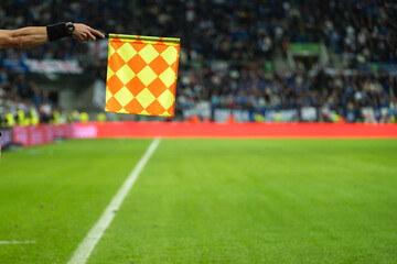 Raised flag in the hand of soccer sideline referee during football match.