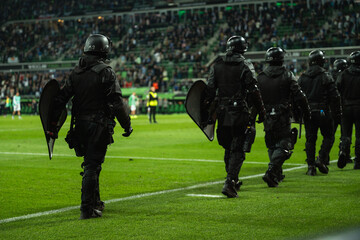 Security guards armed with shields on the football pitch during a soccer match