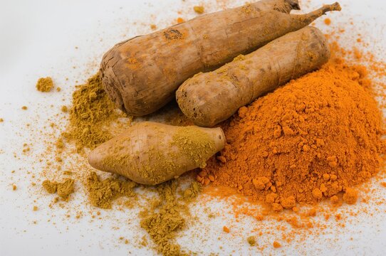 Bright turmeric powder and fresh root, nutritious spice for plant-based cooking