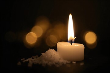 Close-up of a lit candle with sea salt and glowing bokeh lights in the background, symbolizing a spiritual theme.