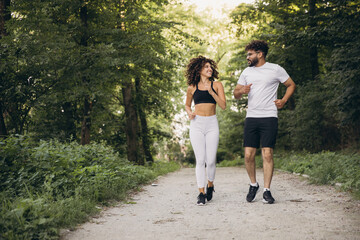 Fototapeta premium Young multi ethnic couple running in a park enjoying workout together