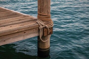 A boat dock corner with ropes coiled around posts by the lake.