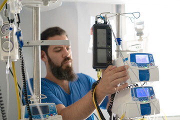 Male nurse adjusting infusion pump in intensive care unit