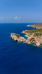 Zakynthos Greece coastline aerial view of Rock Arch with steep rocky cliffs green hills and deep blue Ionian Sea stretching to horizon 