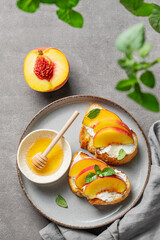 Toast bruschetta with peach, nectarine, cream cheese or ricotta and honey on a plate on a dark background