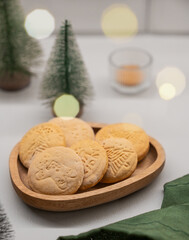 Festive gingerbread cookies with festive patterns on a wooden plate on a light background