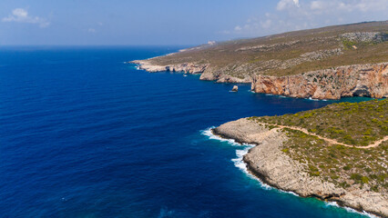 Zakynthos Greece rocky coastline with rugged cliffs and green hills meeting the deep blue Ionian Sea under clear sky aerial summer view
