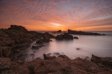 Obraz premium Beautiful long exposure sunset over a rugged shoreline. Scenic natural view.