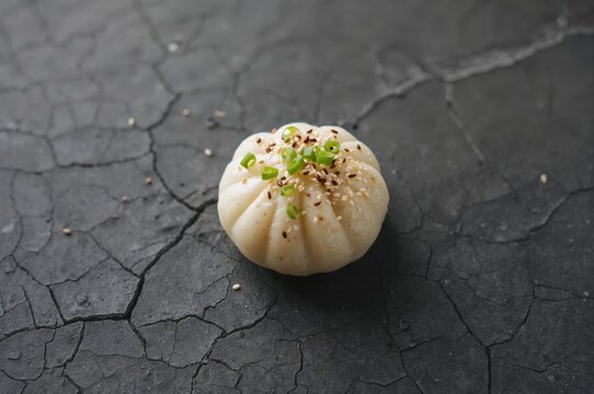 Traditional steamed tin-puns or pigodi from Korea, captured in a studio with a dark grey cracked stone backdrop