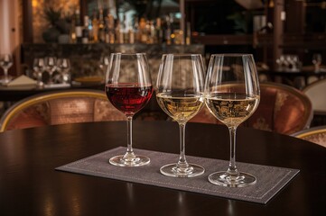 Three glasses containing white wine, amber wine, and water arranged on a tasting mat at a wine tasting event held at a vacation spot.