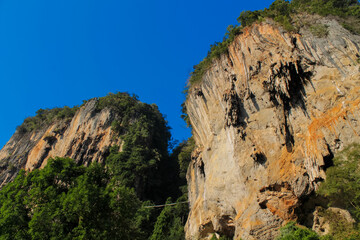 Cliffs, palm trees and sandy beach in Krabi, Thailand, with turquoise sea, limestone formations, and tropical vegetation under clear sky, showing coastal landscape travel destination in Andaman sea