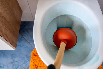 Pömpel in einer Toilette als Symbol für ein verstopftes Rohr