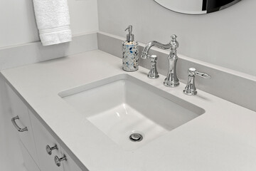 Bathroom sink with a soap dispenser and a towel rack above it