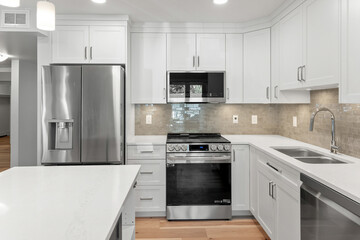 Fototapeta premium Clean and modern kitchen with a stainless steel refrigerator, microwave
