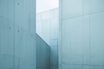 Fototapeta premium Architectural close-up of a modern cement facade featuring diverse geometric patterns in soft blue shades with interplay of light and shadow, minimalist style.