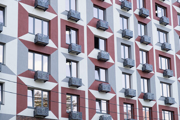 Modern low-cost residential building with repeating windows and small decorative balconies, representing affordable housing in dense city neighborhood.