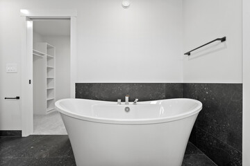 White bathtub with a black border sits in a bathroom