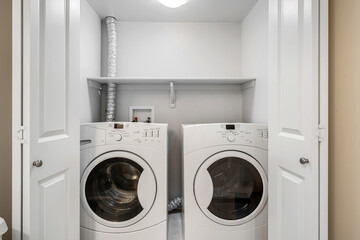 White dryer and a white washing machine are in a small room