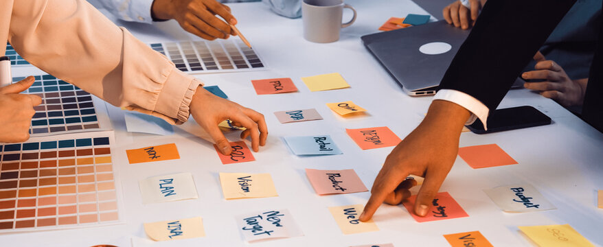A vibrant workspace showcasing a team engaged in a brainstorming session. Colorful sticky notes and swatches reflect creative planning and collaboration efforts. SACTR