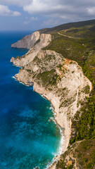 Aerial view of Zakynthos Greece towering coastal cliffs above turquoise blue Ionian Sea with scenic boat cruising under cloudy summer sky