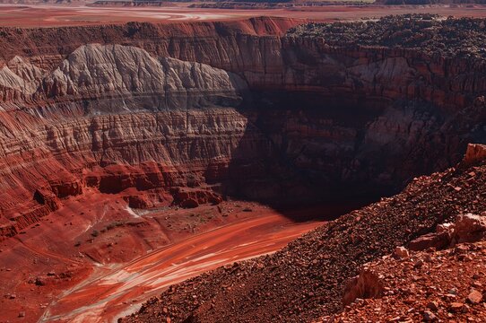 Open deep excavation of red iron ore with multi-level shadows in a remote mining area