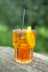 Typical Italian cocktail called spritz served in a glass tumbler resting on a wooden table
