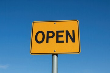 Yellow road sign displaying the word 'open' against a backdrop of clear blue sky