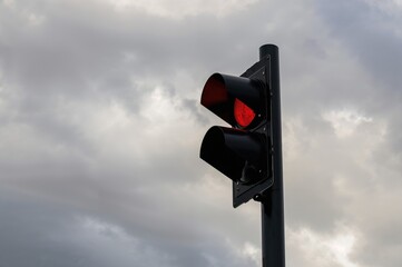 Outline of a crimson traffic signal against a cloudy backdrop
