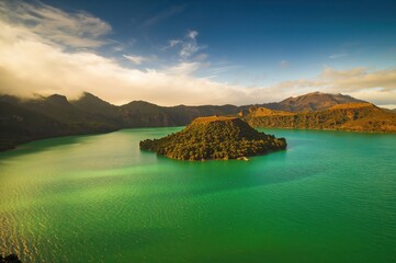 Cloud shadows cast over a lush volcanic lake