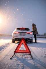 Emergency Breakdown in Snowy Landscape with Hazard Triangle and Woman Seeking Help