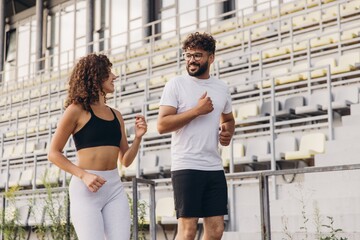 Fototapeta premium Happy arab couple running together in a stadium