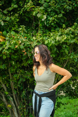 Fototapeta premium Smiling woman portrayed in the countryside in front of a large tree. The woman is a beautiful thirty-eight year old brunette of Caucasian origin