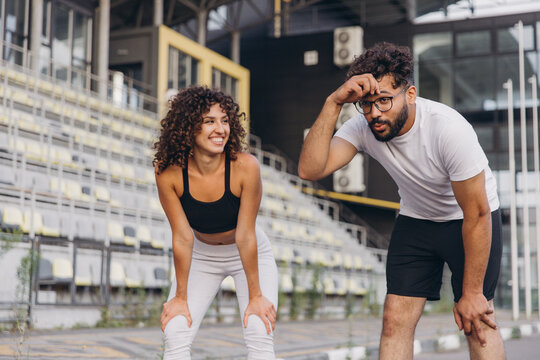 Exhausted arab couple resting after running in a stadium - Powered by Adobe