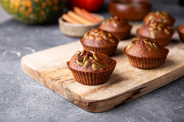 Autumn pumpkin cupcakes or baked muffins with fresh pumpkin and pumpkin seeds for Thanksgiving day close up