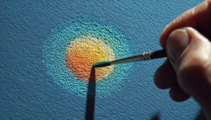 Hand holding brush, applying paint to create a circular design on a textured canvas