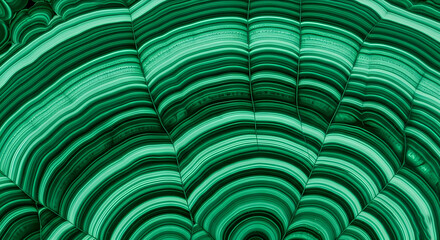 Close-up of a malachite stone displaying intricate green patterns and layers. The stone features smooth, wavy lines and a rich, vibrant color.
