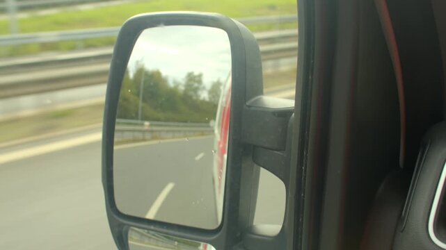 This video follows a truck on a highway, featuring closeups of side view mirrors from a truck and car, showcasing reflections and scenery