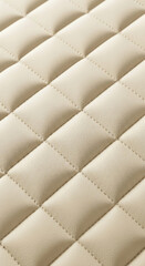 Fototapeta premium Beige quilted leather texture close-up, showing soft, smooth surface and diamond stitching, ideal for background or luxury design