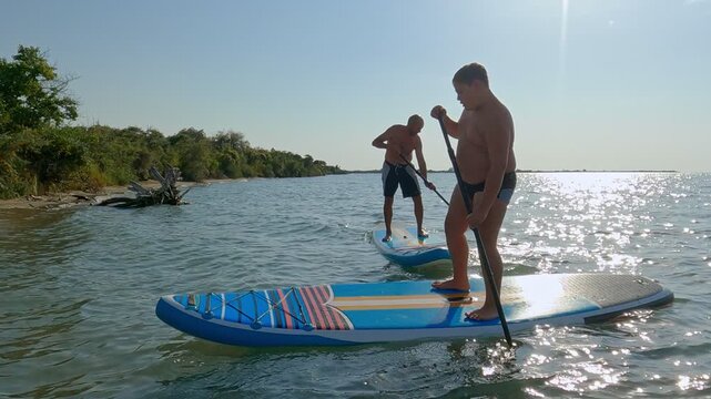 An uncle teaches his nephew to sail on a SUP board on a Beautiful Mountain Lake.
Paddle board stand-up paddleboard beach lifestyle banner. Summer vacation leisure activity.