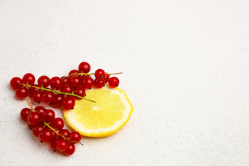 Fresh red currants and lemon slice arranged on a light background for culinary use
