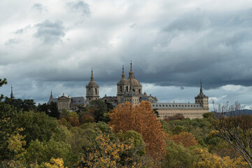 Fototapeta premium views of the Monastery of El Escorial and its historic gardens surrounded by autumn trees and spectacular skies.