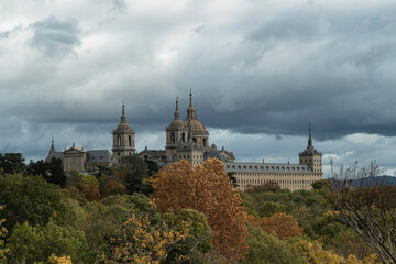 Obraz premium views of the Monastery of El Escorial and its historic gardens surrounded by autumn trees and spectacular skies.